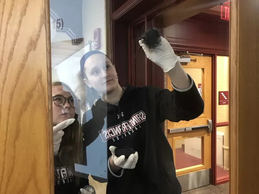 students lifting fingerprints off of a classroom door in Schwab Hall for the Criminal Investigations Class